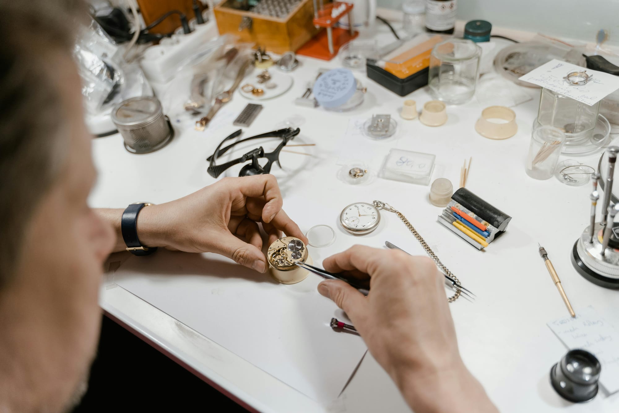 Overhead view of a watchmaker's organized workbench with precision tools spread out
